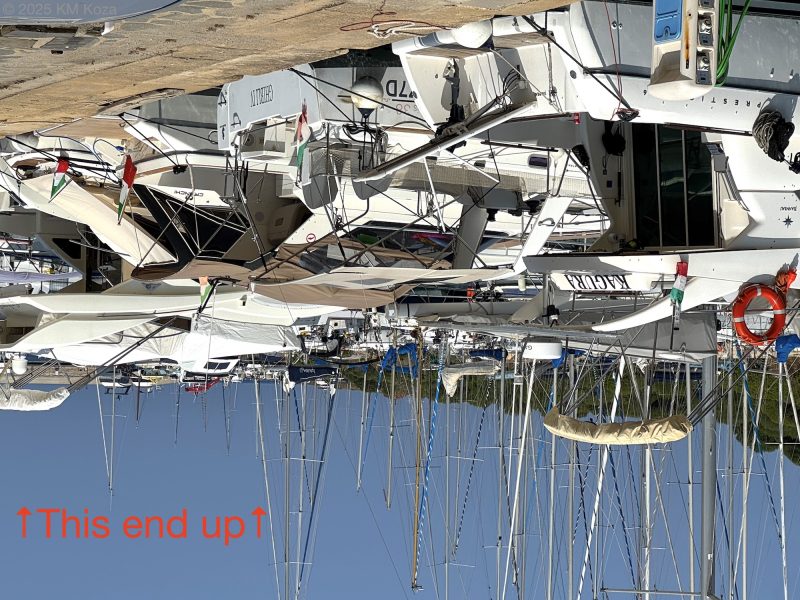 Intentionally upside down photo of sailboats in a harbor.