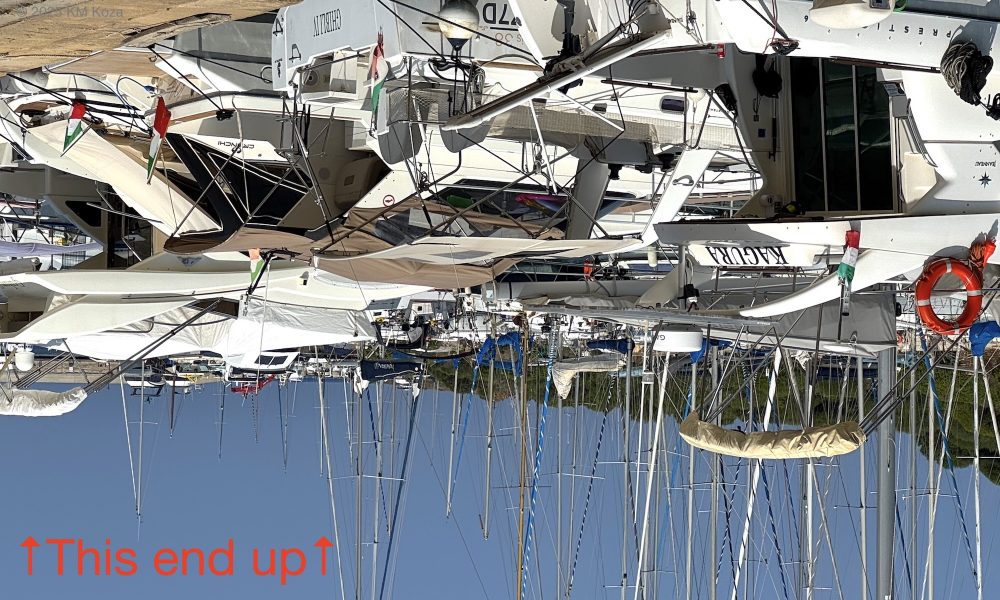 Intentionally upside down photo of sailboats in a harbor.