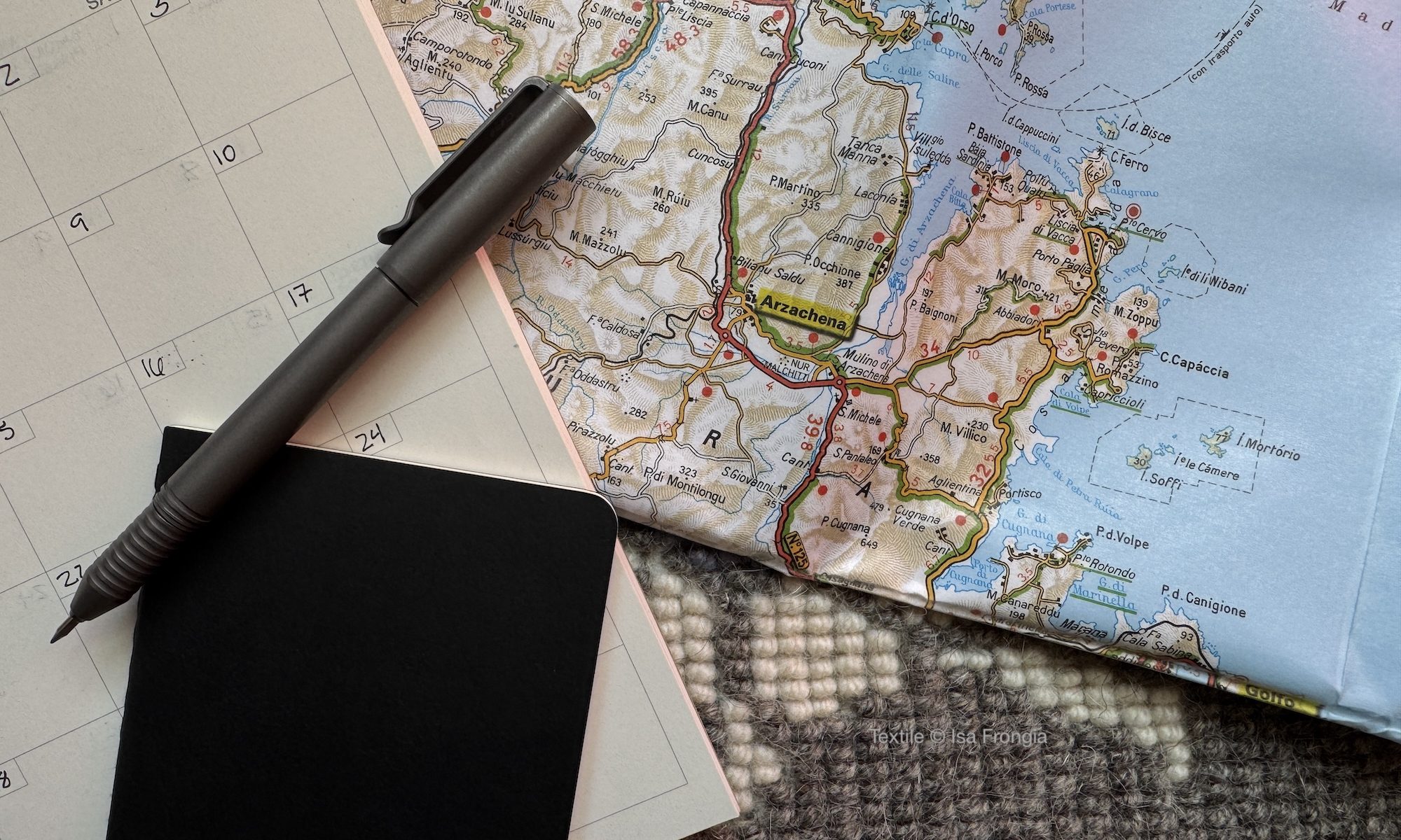 Photo of map, pen, calendar, and pocket sized notebook.