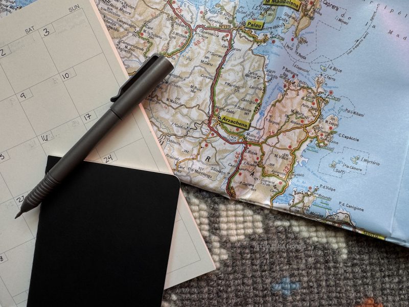 Photo of map, pen, calendar, and pocket sized notebook.
