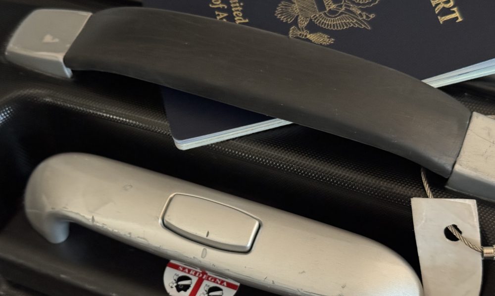 Photo of suitcase handle and corner of passport.